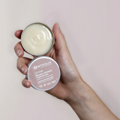 BAUME MULTI-USAGES DE MARQUE CENTIFOLIA À LA FRAGRANCE DOUCEUR FLEURIE EMBALLAGE OUVERT PRÉSENTER DANS UNE MAIN