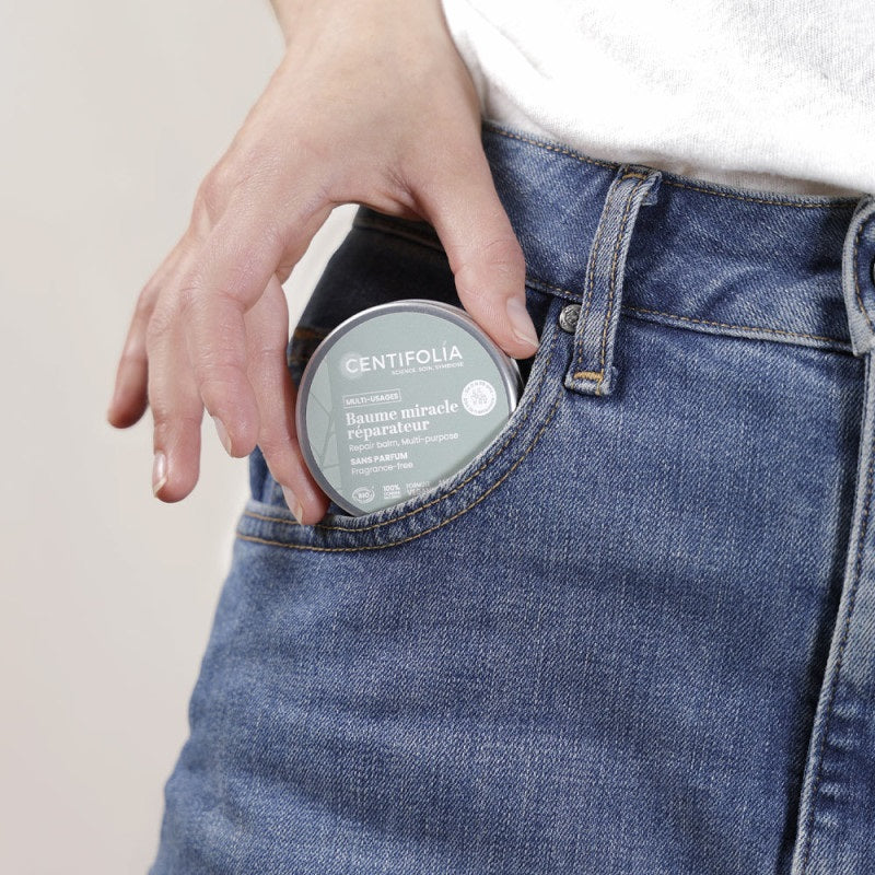 BAUME MULTI-USAGES DE MARQUE CENTIFOLIA SANS PARFUM EMBALLAGE FERMÉ EN TRAIN D'ÊTRE MIS DANS UNE POCHE DE JEANS