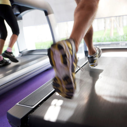 CLOSE UP SUR DES PIEDS QUI COURS SUR UN TAPIS ROULANT