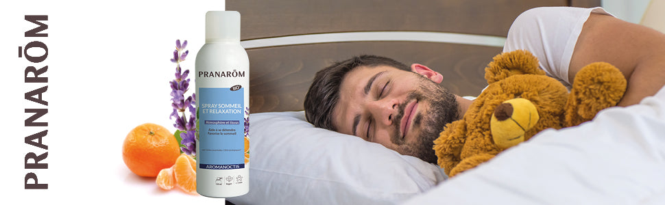 homme au lit avec bouteille AROMANOCTIS – Spray sommeil relaxation - BI0 et  un bouquet de fleurs et fruits sur le côté